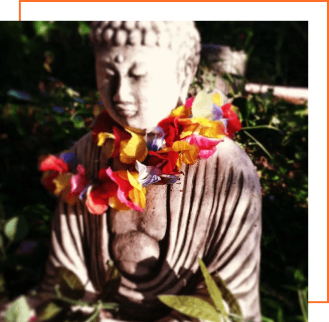 A statue of buddha with flowers around it.
