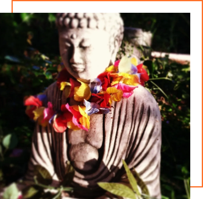 A statue of buddha with flowers around it.