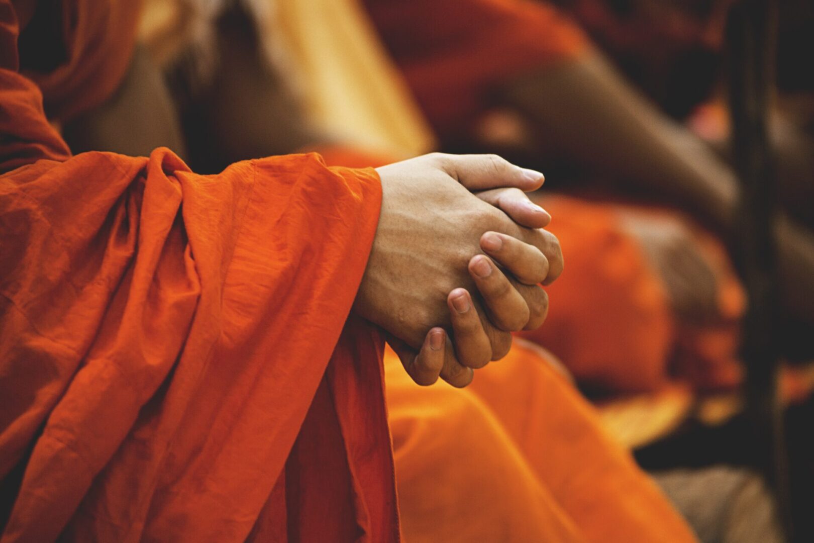 A person in orange robes holding their hands together.