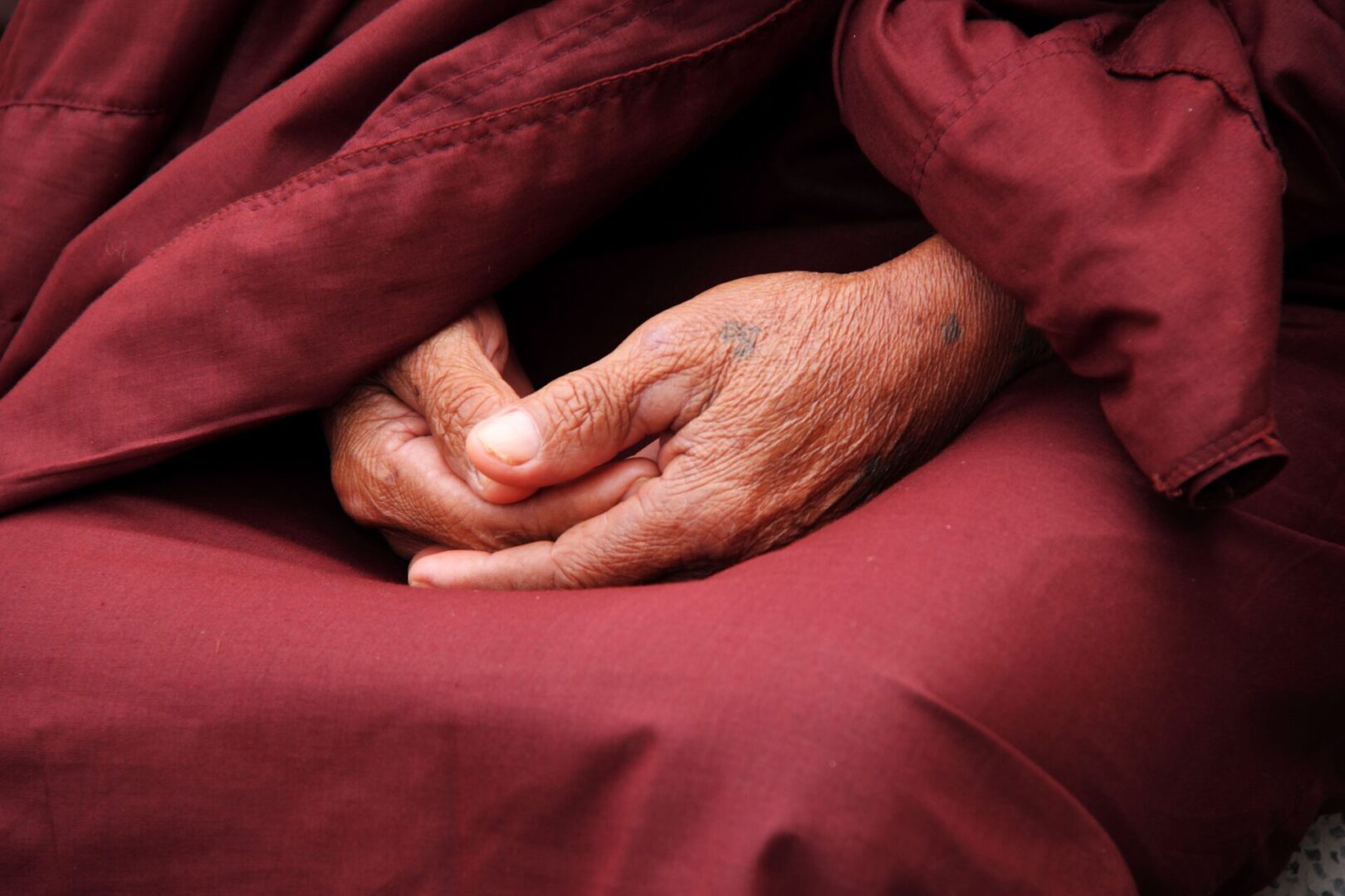 A person 's hands resting on top of a blanket.