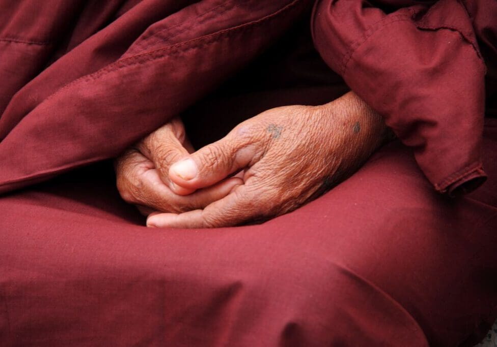 A person 's hands resting on top of a blanket.